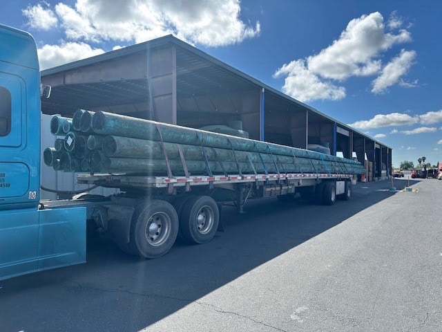 A row of freshly treated, large-diameter timber pilings